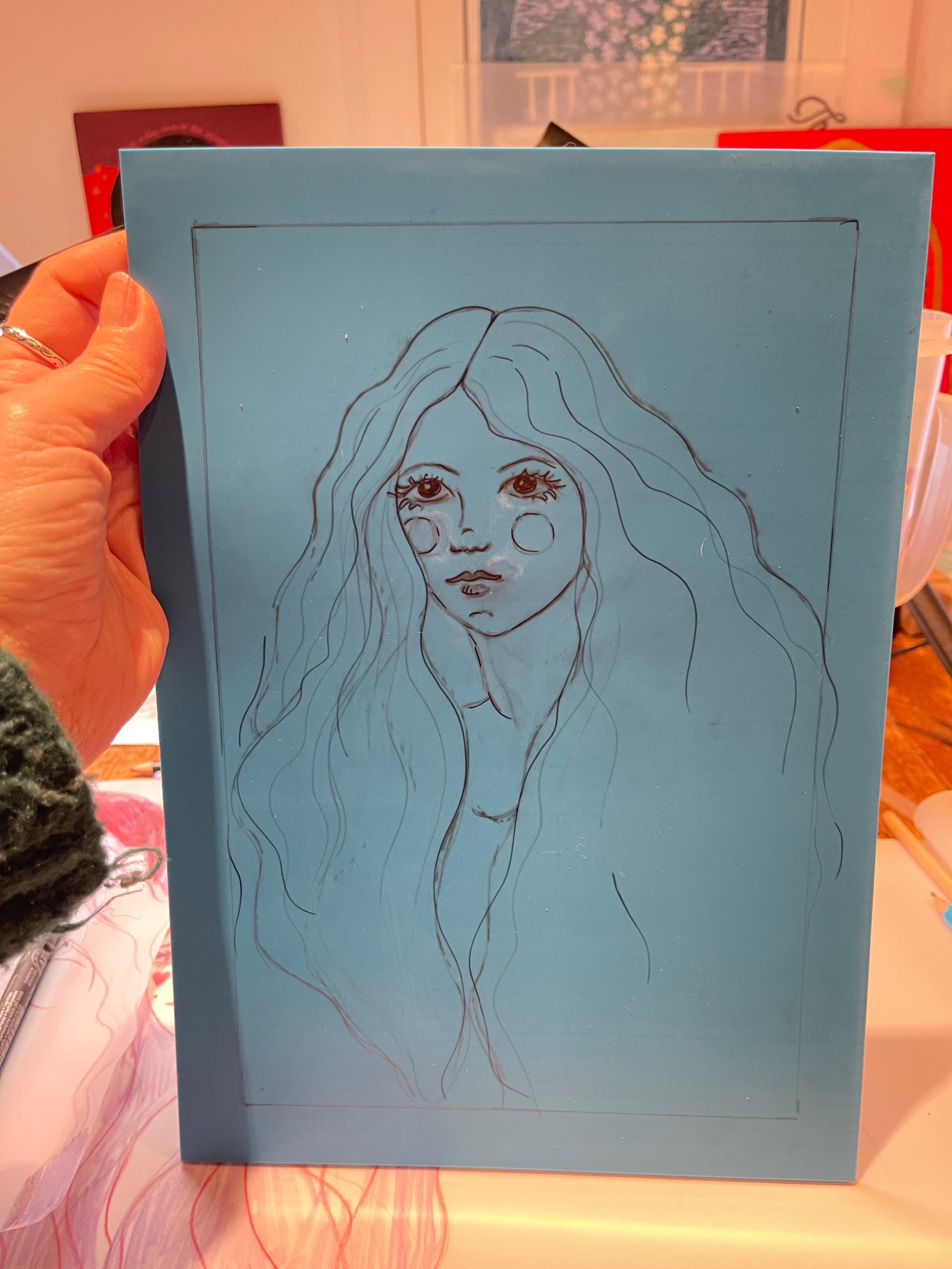 A hand holding a lino block with a drawing ready to be carved